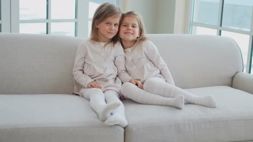 Two Cute Girls Sitting Together on Couch