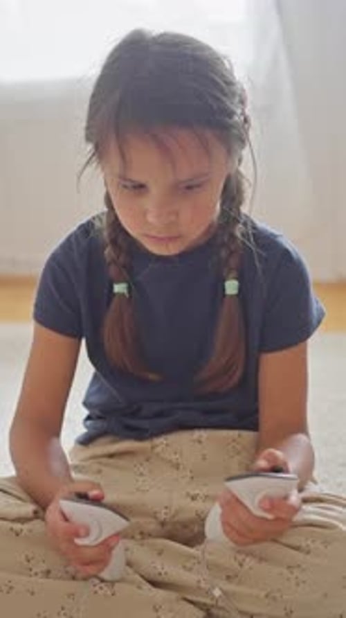 Attentive Girl on Lap Comparing Controllers Soft Window Light Braided Pigtails Steady Grip on