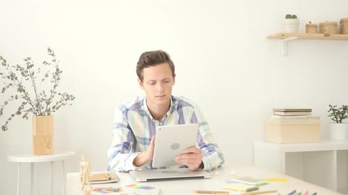 Man Using Tablet at Desk with Laptop