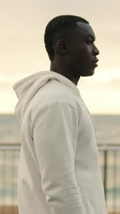 Side view of handsome athlete man walking down the boardwalk, feeling tired after street workout