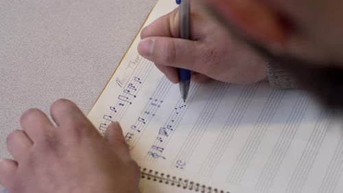 Man Hands Writing Music Notes On Blank Music Sheet - Close Up Shot