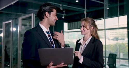 Businesswoman listening to male colleague sharing idea using laptop during professional office