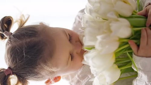 Girl Smelling Bouquet of White Tulips