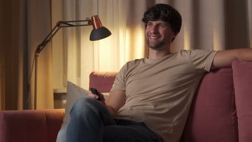 Man Relaxing on Couch, Watching Television