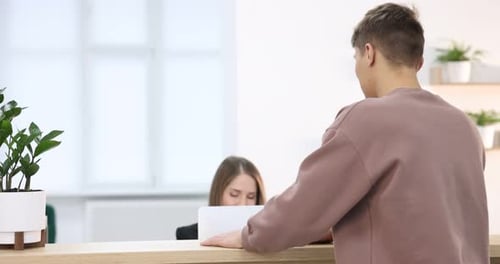 Receptionist working with guest at reception desk indoors