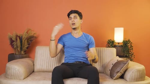 Man Fanning Neck While Sitting on Couch