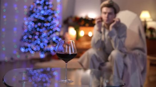 Closeup Glass of Red Wine on Glass Table with Blurred Depressed Caucasian LGBT Man at Background