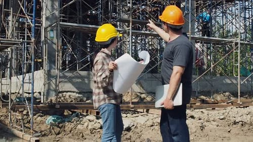 Construction manager and engineer discussing and checking plans on construction site.
