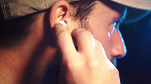 Man Inserts Wireless Earbud in Ear, Close Up