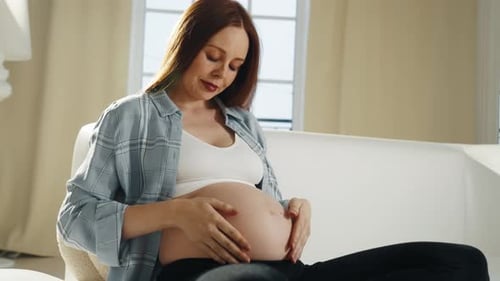 Smiling Pregnant Woman Holds Her Belly at Home