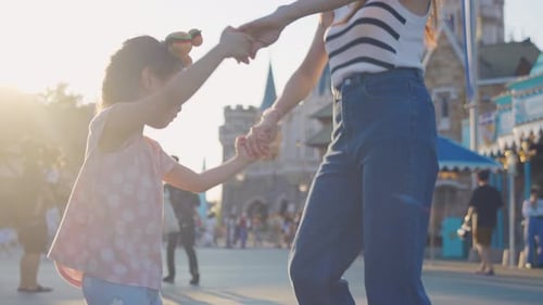 Asian mother and adorable kid daughter walking at the theme park.