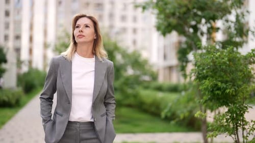 Erwachsene Dame im Business-Anzug geht im Sommer alleine im modernen Viertel der Großstadt spazieren Medium Shot
