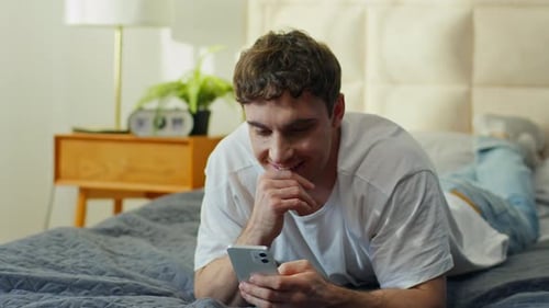 Man Relaxing on Bed while Using Smartphone