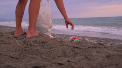 Un homme méconnaissable nettoie les ordures au coucher du soleil au bord de la mer ou de l'océan,