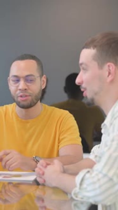 Two Men Talking at a Table Indoors