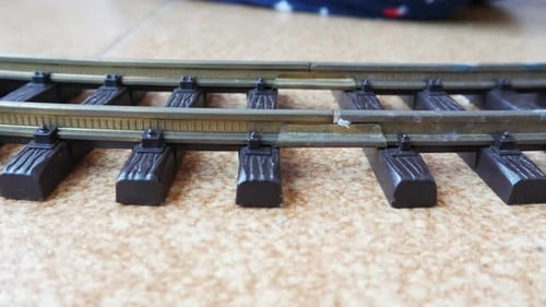 Train and railroad toy with a child playing in the background