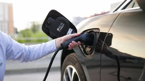 Man Charging Electric Car Giving a Thumbs Up