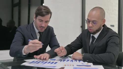 Business Meeting Discussing Financial Charts in Office