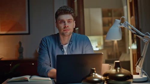 Man Works on Laptop Computer at Night