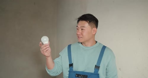 Man Holding Lightbulb in Unfinished Interior