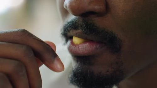 Nahaufnahme eines Mannes, der beim Essen im Haus Fritten beißt und die Finger die Lippen berühren