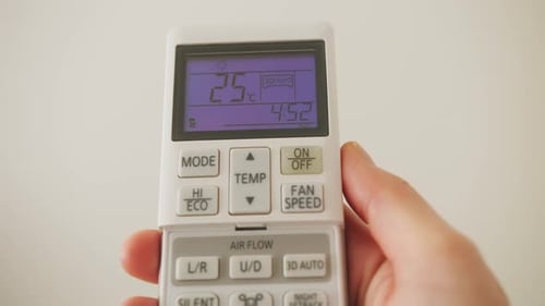 Hand Adjusting Temperature on Air Conditioner Remote Control