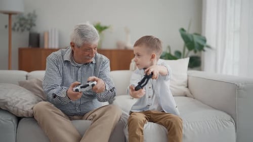 Grandfather and Grandson Playing Video Games on Sofa