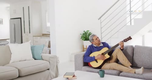 Senior Man Plays Guitar on Couch at Home