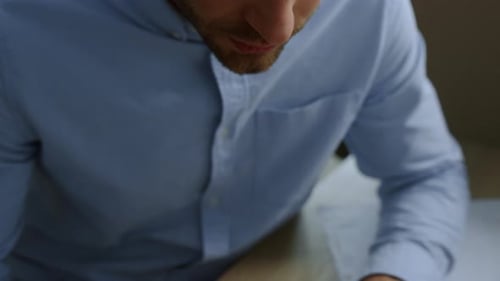 Man Writes in Notebook at Desk in Office