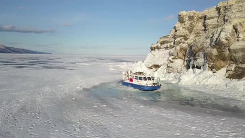 Ein wunderschöner eisbedeckter See mit einem Boot in der Nähe einer felsigen Küstenlinie
