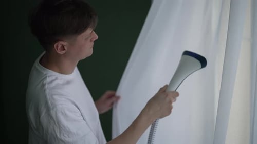 Young Adult Steaming White Curtains at Home