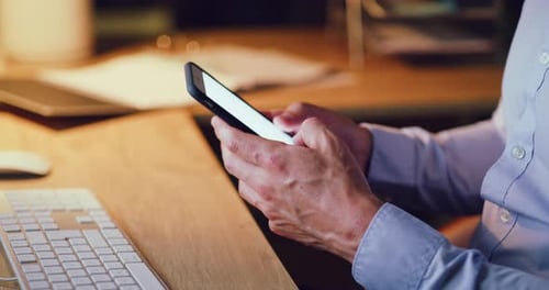 Gros plan d'un homme d'affaires la nuit envoyant des textos sur un téléphone avec un écran blanc dans un bureau