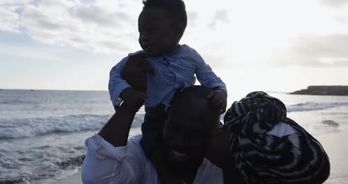 African Parents And Cute Little Son Having Fun On The Beach At Sunset - Family People And Love