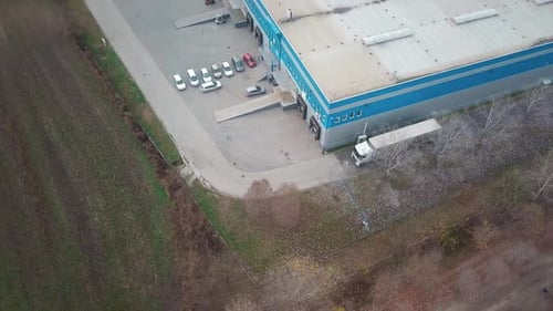 Aerial shot of a cargo truck moving next to an industrial building