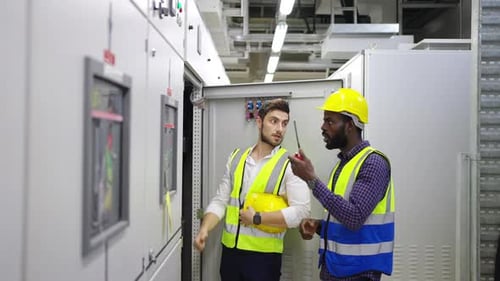 4K Two engineer working at factory server electric control panel room