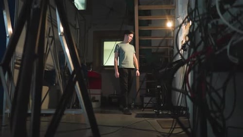 Man Adjusts Cables on Set in Studio