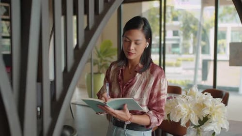Asian Woman Making Notes in Notebook