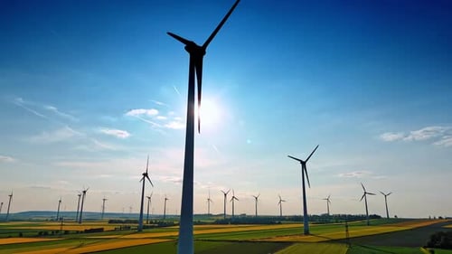 Wind Turbines Silhouetted Against Blue Sky Over Fields