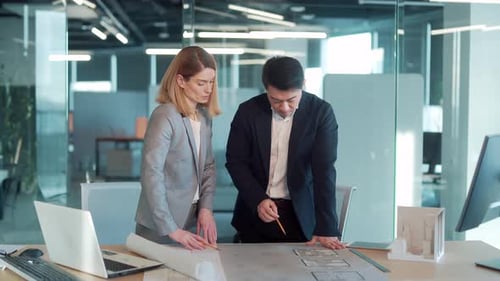 Architects Reviewing Blueprints Together in Modern Office
