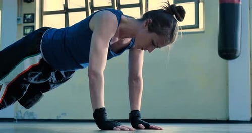 A professional boxer girl in the gym works with a punching bag, a technique of striking, a rack, p