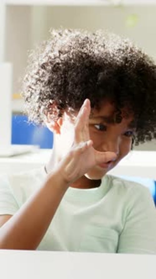Vertical video: Gesturing student in mint tee glancing and reaching, offering at desk, laptop