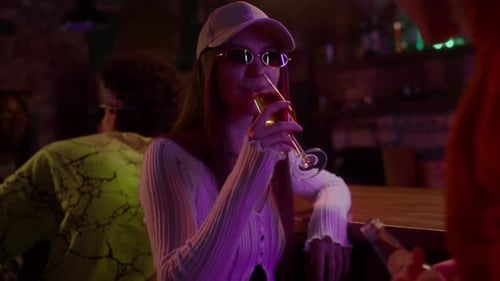 Young Woman Drinking Champagne and Chatting with Guy in Club