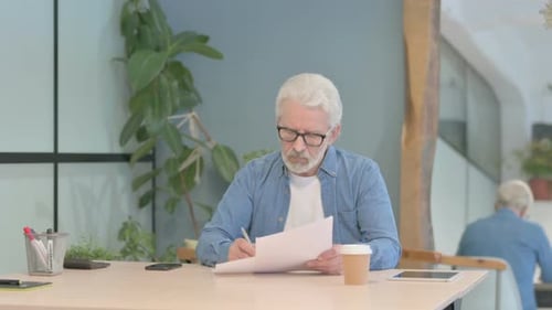 Senior Man Reviewing Documents at Desk