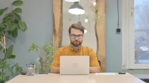 Man at Desk Working on Laptop Gives Thumbs Up