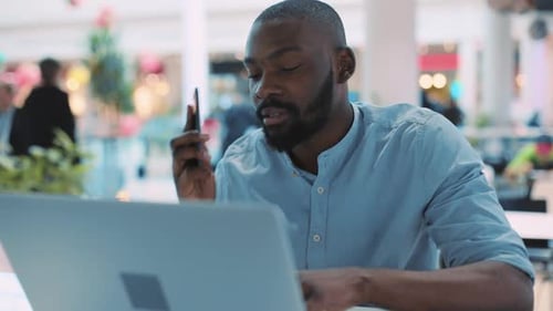 Close Up African American Young Man Uses Laptop Talk Phone in Cafe Serious Portrait Close Up Face
