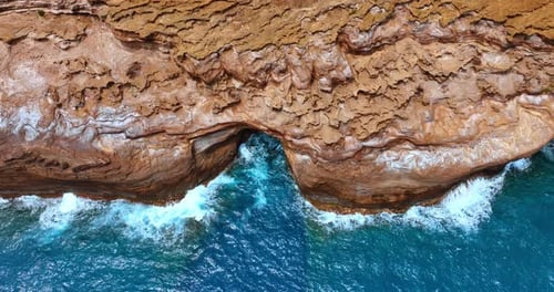 Azure water and waves splashing by the brown rocks and caves.