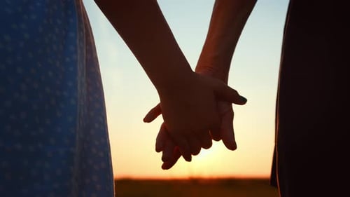Closeup Romantic View of Couple Holding Hands Against Blurred Sky and Sunset