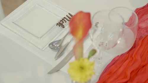 Elegant wedding table setup with cutlery, flower centerpiece, and decorative accents