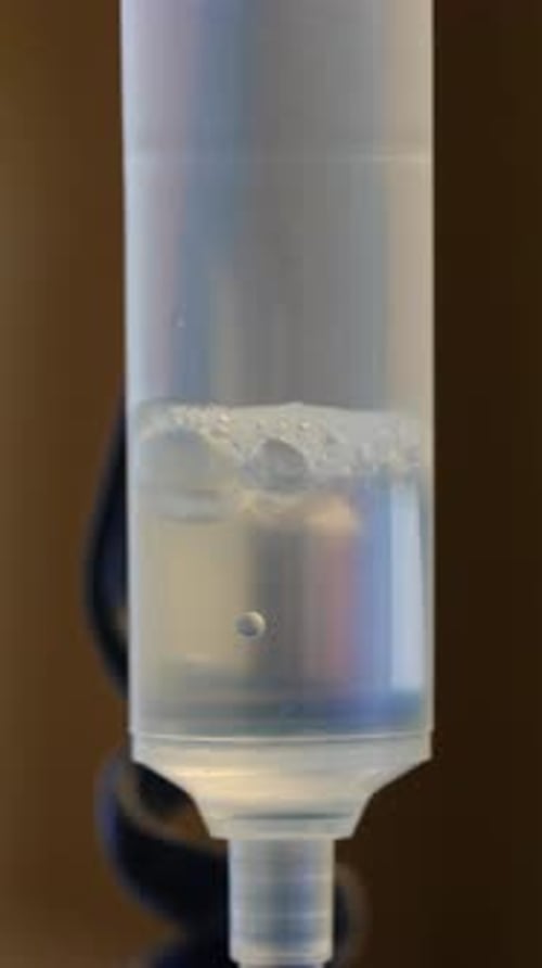 Makroansicht der intravenösen Tropfkammer mit absteigendem Flüssigkeitstropfen, der die Präzisionsflüssigkeit hervorhebt