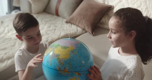 Children explore world globe at home